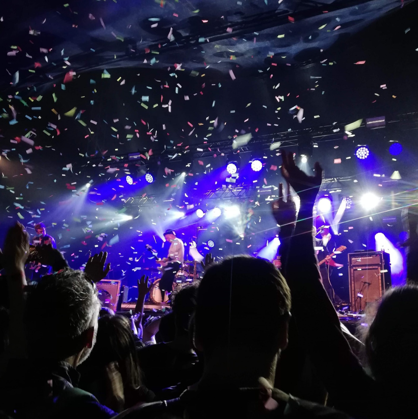 A crowd in a dimly lit room where confetti is falling from the roof