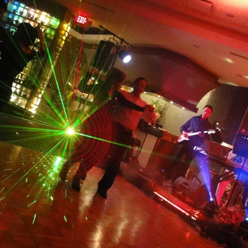 A couple dancing on a dancefloor while a band plays live music in the background